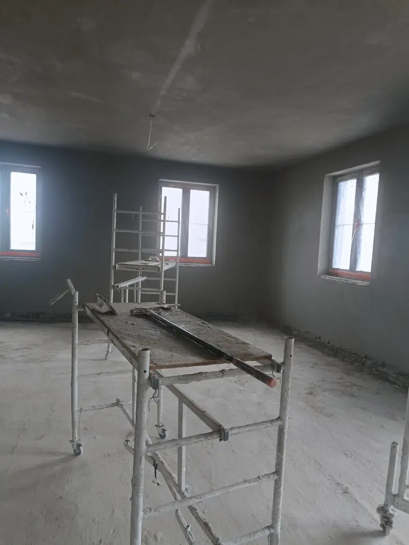 Pomieszczenie z rusztowaniem przy ścianie w trakcie tynkowania