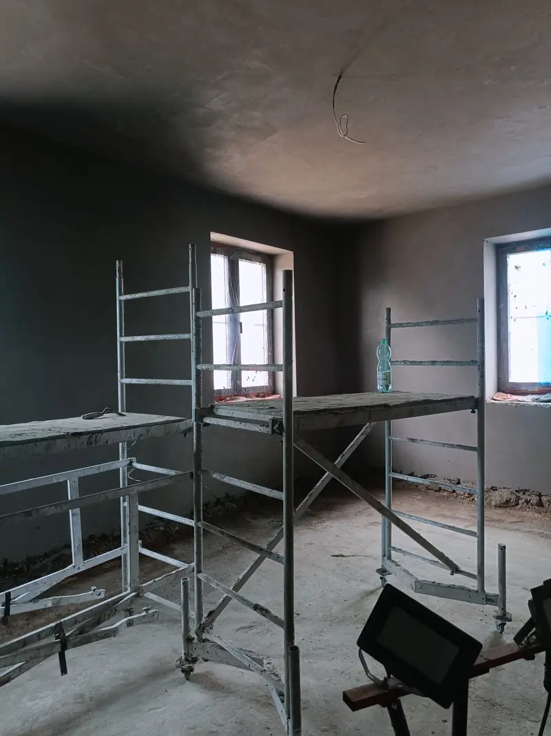 Pomieszczenie z rusztowaniem przy dużym oknie, ściany po tynku