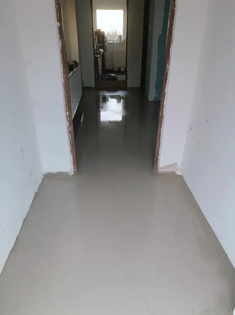 Pokój z dużym oknem, ściany po tynku, drabina i grzejnik pod oknem